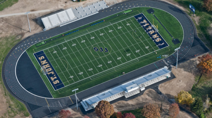An aerial view of a track and football field, an educational construction project supported by the team at Miller Diversified