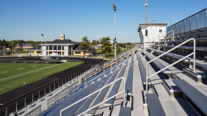 Stadium bleacher rows and a football field with track from a commercial construction project by Miller Diversified