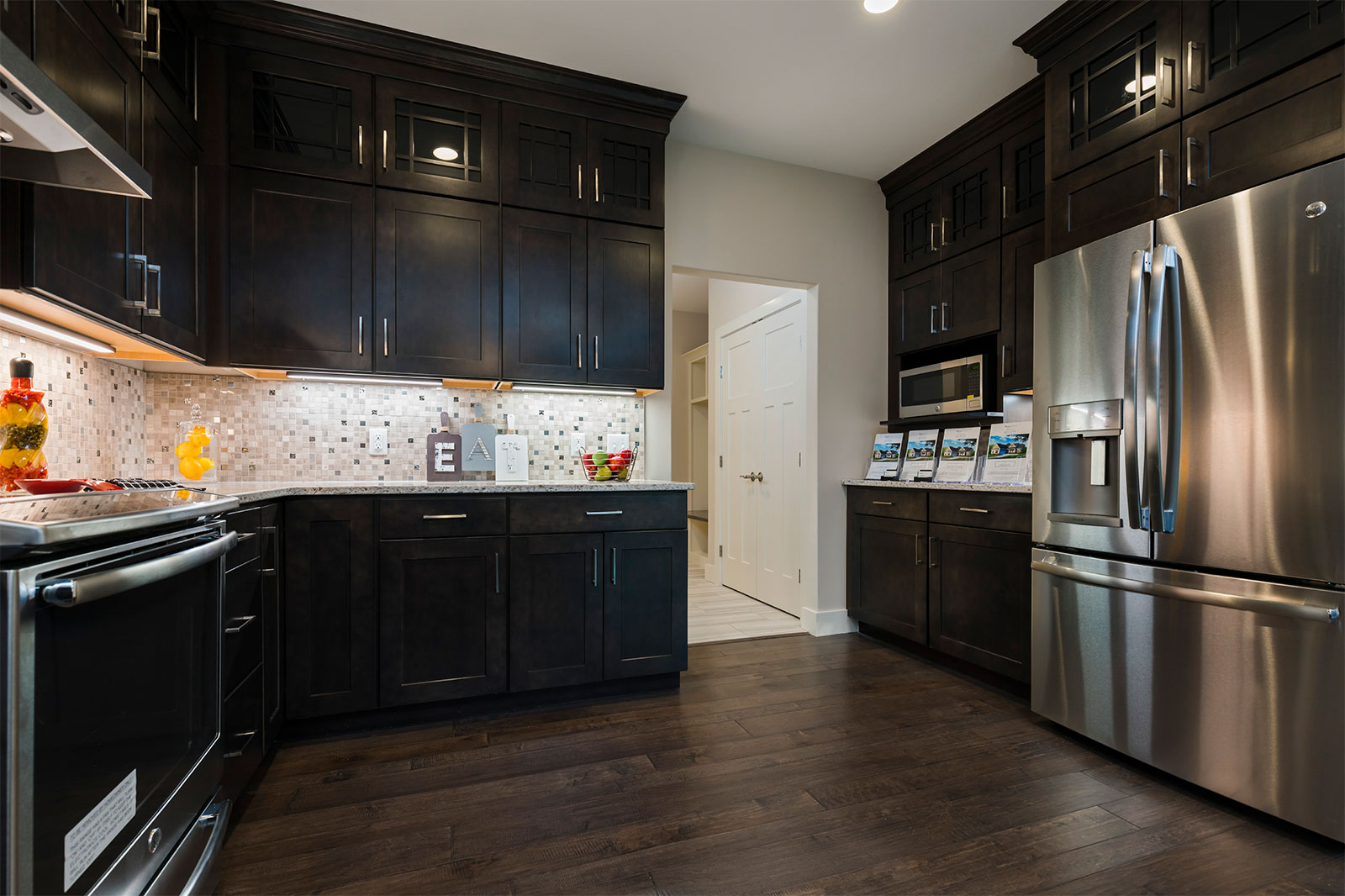 A kitchen with black cabinets and stainless steel appliances from a luxury home at the Villas at Blystone in Monclova, Ohio, constructed by the team at Miller Diversified